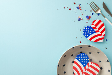 Plan for Independence Day USA with inventive table arrangement. Top view of plate, silverware, hearts featuring American flag patterns, confetti on pastel blue backdrop with space for text or advert
