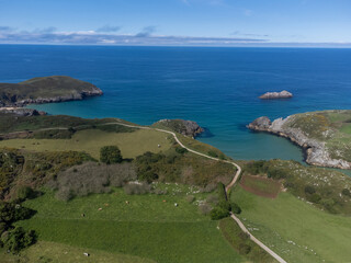 Aerial view on Playa de Poo during low tide near Llanes, Green coast of Asturias, North Spain with sandy beaches, cliffs, hidden caves, green fields and mountains.