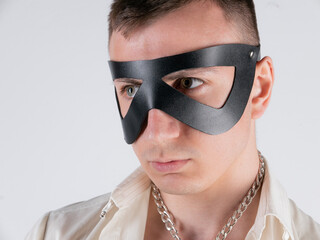 white man with a short haircut in a bdsm leather mask on a light background
