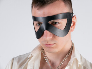 white man with a short haircut in a bdsm leather mask on a light background