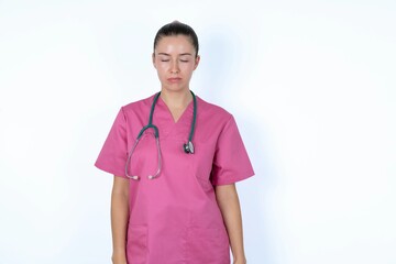 young caucasian doctor woman wearing pink uniform over white background crying desperate and depressed with tears on his eyes suffering pain and depression. Sad facial expression and emotion concept.