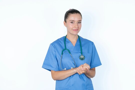 Photo of cheerful confident young caucasian doctor woman wearing medical uniform over white background arms together