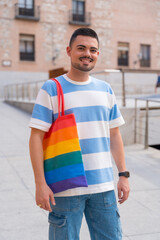 Portrait of gay man with a rainbow lgbt bag in the city, pride party and homosexual