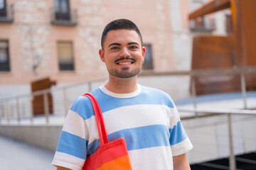 Portrait of smiling gay man with rainbow lgbt bag in the city, pride and homosexual party
