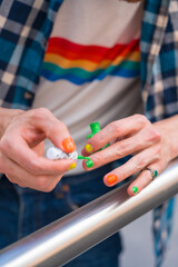 Attractive gay man painting his nails makeup with rainbow lgbt flag in the city, pride party and...