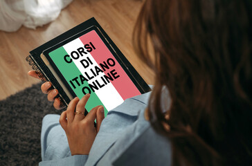 A woman holds a tablet in her hands on the screen of which it is written - Online Italian courses