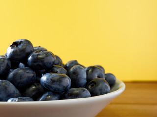 Freshly picked blueberries in a white vintage ceramic bowl. Selective focus, Free text space.