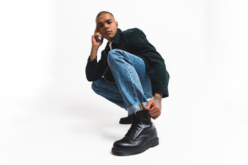 Afro American male model in denim jeans sitting on the floor posing studio shot. High quality photo