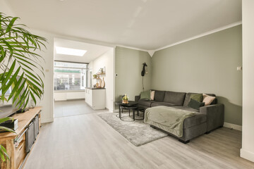 Fototapeta na wymiar a living room with wood flooring and green wall paint on the walls there is a grey couch in front