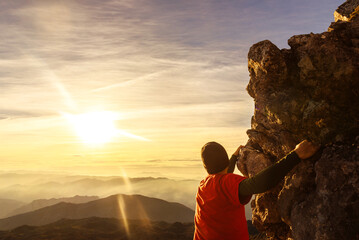 unrecognizable man climbing a mountain without a rope contemplating the landscape at sunset. sport and adventure.