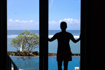 silhouette of a woman looking at the sea view from the bedroom window.