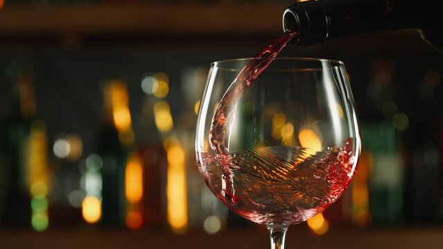 Super Slow Motion Shot of Pouring Red Wine into Glass Before Bar at 1000fps.