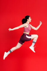 Fototapeta na wymiar Focused competitive determined sportswoman jumping high, fast running