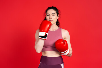 Confident young athlete woman, professional boxer fighter posing in boxing gloves