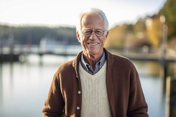 Portrait of smiling senior man standing at riverside during sunny day