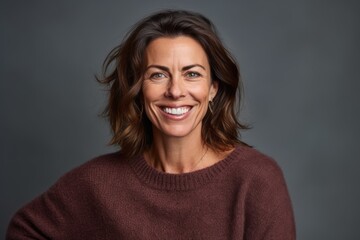 Fototapeta premium Portrait of a smiling woman in a sweater on a gray background