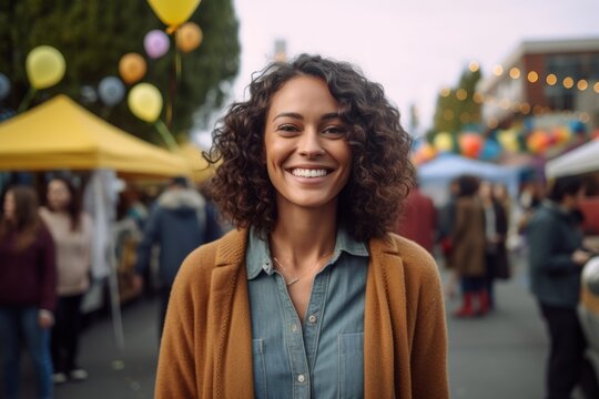 Medium shot portrait photography of a grinning woman in her 30s that is wearing a chic cardigan against a neighborhood block party with food and games background .  Generative AI
