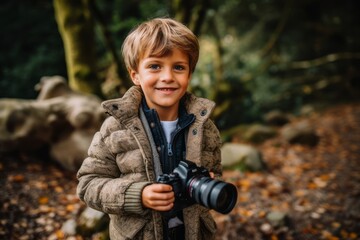 Cute little boy with camera in autumn forest. Outdoor portrait.