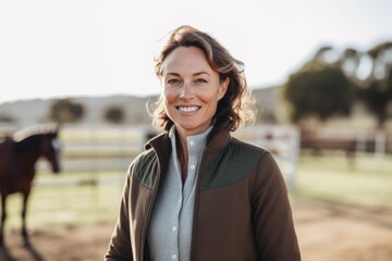 Obraz premium Medium shot portrait photography of a grinning woman in her 40s that is wearing a chic cardigan against a beautiful horse ranch with riders taking lessons background . Generative AI