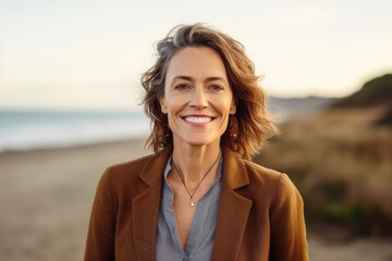 Portrait of smiling middle aged woman standing on beach at seaside