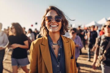 Happy young woman in sunglasses standing in front of crowd at music festival