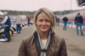 Fototapeta premium Portrait of a beautiful woman with blond hair on the background of the race track