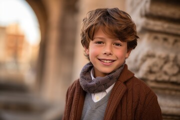 Portrait of a smiling boy wearing a brown coat and scarf outdoors