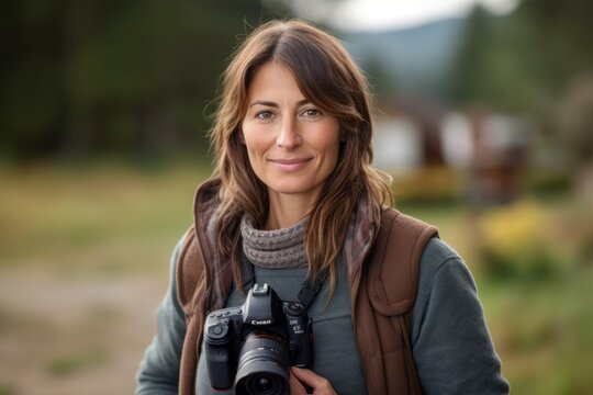 Portrait of smiling female photographer with digital camera in the countryside.