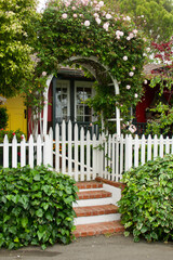 cottage with rose covered trellis and white picket fence
