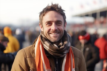 Naklejka premium Medium shot portrait photography of a grinning man in his 30s that is wearing a charming scarf against an exciting race car event with pit crews working background . Generative AI