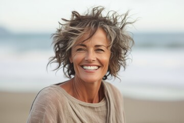 Portrait of smiling mature woman with hair flying in the wind on the beach
