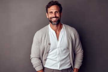 Cheerful man looking at camera and smiling while standing against grey background