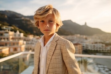 Obraz premium portrait of a beautiful blond boy in a beige jacket on the terrace of a modern house