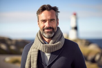Fototapeta premium Portrait of a handsome mature man standing in front of a lighthouse