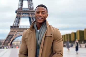happy african american man in beige coat with eiffel tower in background