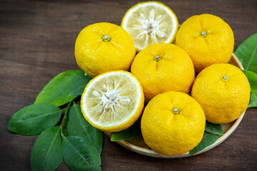 Yuzu Orange fruit in wooden basket over wooden background, Kochi Yellow Yuzu over wooden table.