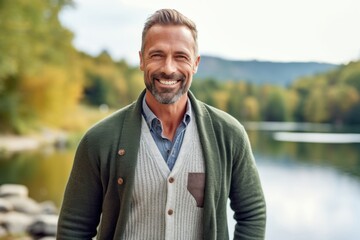 Portrait of a handsome mature man standing by the lake and smiling