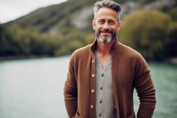 Portrait of a handsome mature man in casual clothes standing by the river.