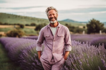 Portrait of happy senior man standing in lavender field at sunset