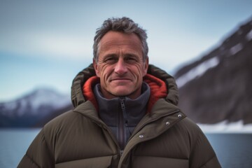 Fototapeta na wymiar Medium shot portrait photography of a satisfied man in his 50s that is wearing a warm parka against a mountain lake or alpine background . Generative AI