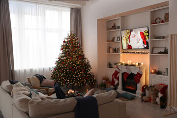 TV set with Christmas movie above fireplace in cosy room. Winter holidays atmosphere