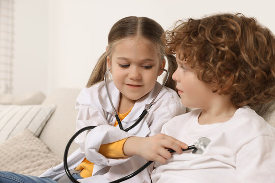 Little girl playing doctor with her friend at home