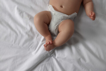 Little baby in diaper lying on bed, top view