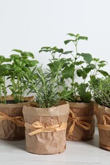 Different aromatic potted herbs on white wooden table