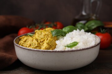 Delicious rice and chicken with curry sauce on wooden table, closeup