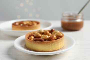 Tartlets with caramelized nuts on white wooden table, closeup. Tasty dessert