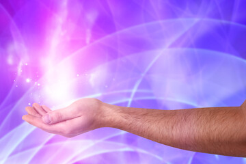 Aura phenomena. Man with flows of energy and lights around his hand against color background,...