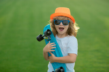 Happy boy laughing and holding skateboard outdoor. Summer fashion kids portrait. © Volodymyr