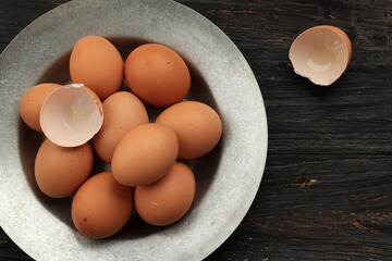 Egg and Egg Shell on Rustic Plate above Wooden Table.