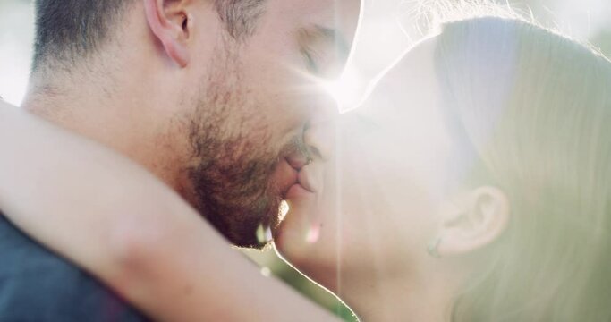 Park, love and couple kiss with lens flare for bonding, romance and loving affection outdoors. Relationship, dating and happy man and woman kissing in nature for quality time, intimacy and commitment
